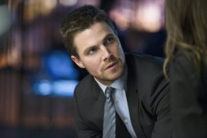 Oliver Queen dressed in a suit is in a serious conversation