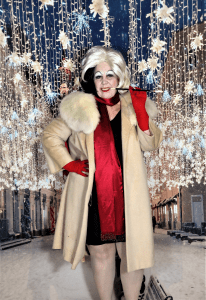 Woman in a red dress and a big white fur coat with black and white split hair is standing in a winter backdrop. 
